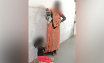 Woman Holds Blood Bag For Transfusion As Daughter Sits On Hospital Floor