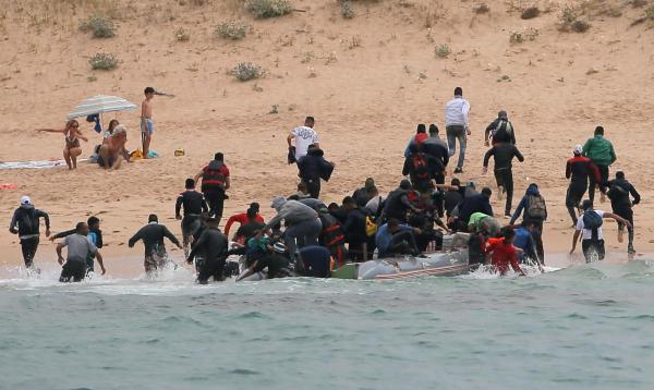 Migrants land on Spanish beach, flee as tourists look on