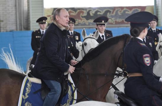 Russia's Putin rides horse with female police ahead of International Women's Day