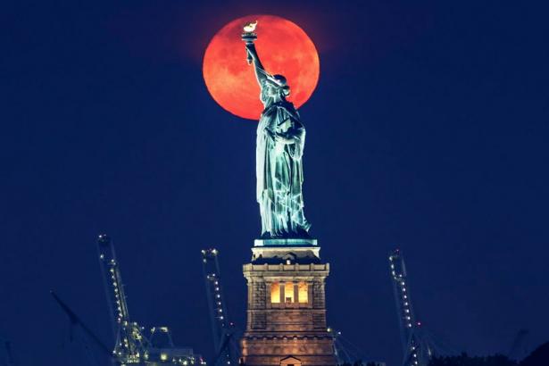 ‘Buck moon’ gives eerie morning backdrop to Statue of Liberty