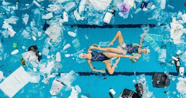 Synchro swimmers perform in a pool filled with plastic